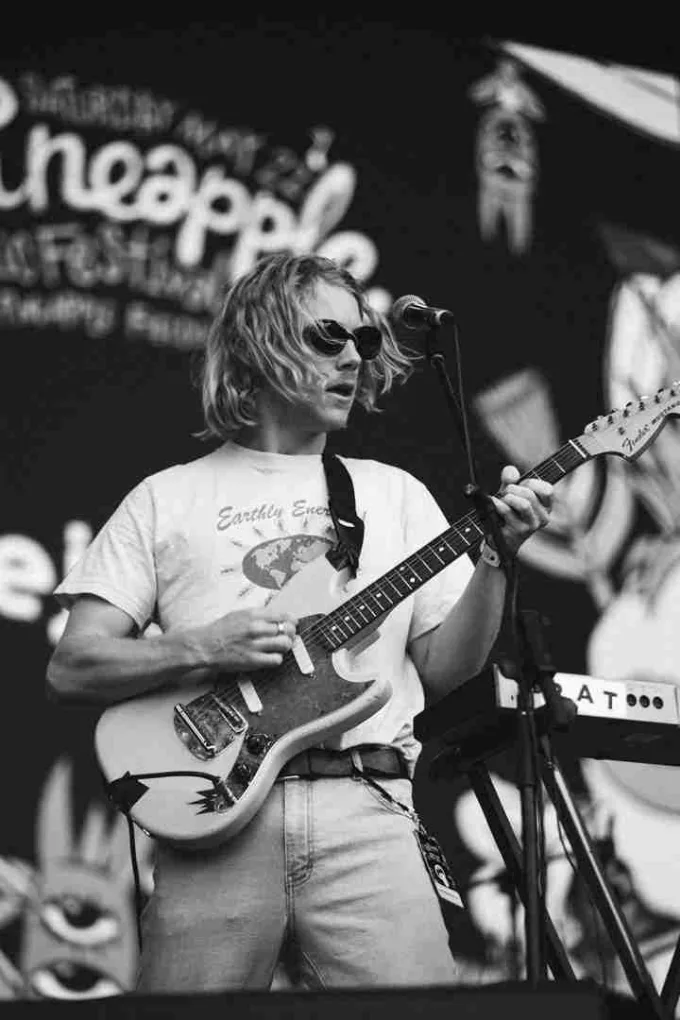 A guitarist on stage at Pineapple Fest, in black and white