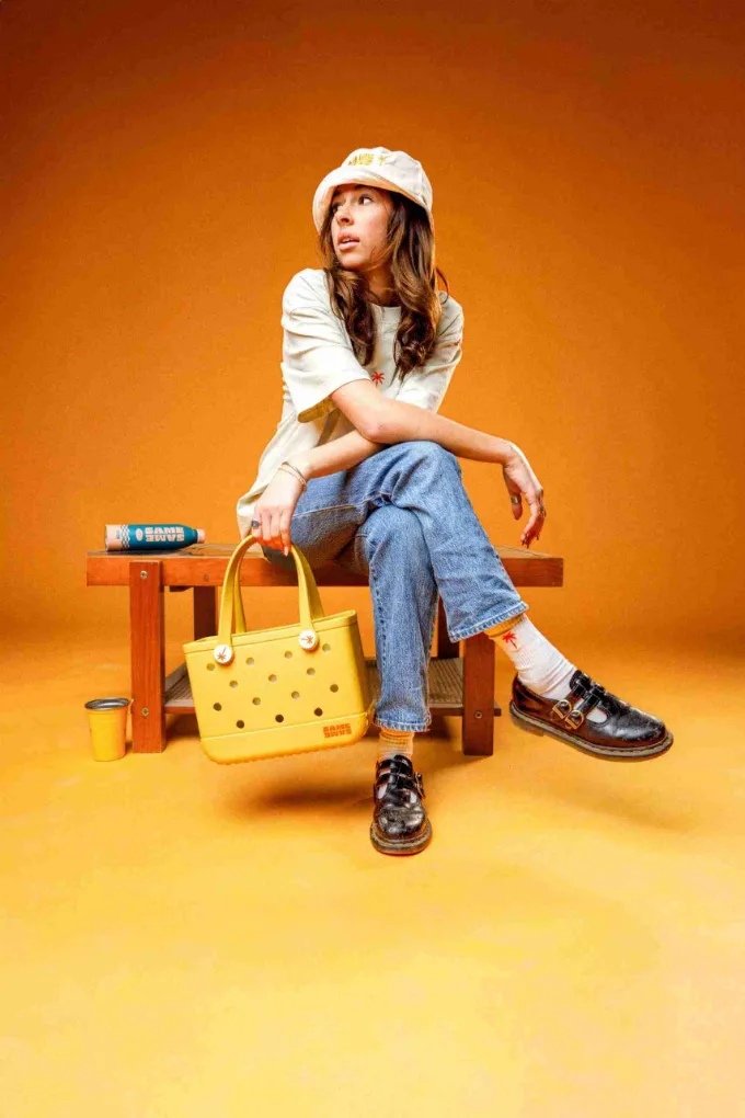 A yellow Same Same tote bag in a fashion shoot on an orange set