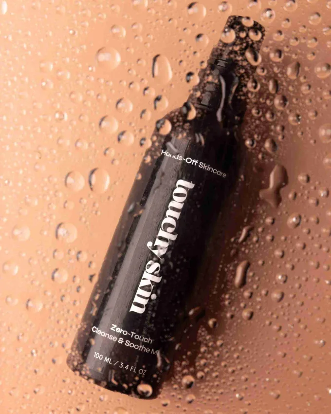 A Touchy Skin bottle covered in water droplets